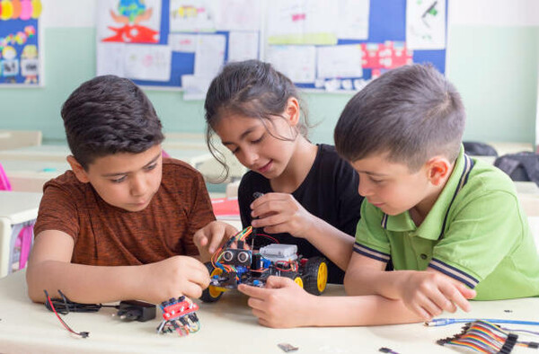 Three young students building a robotic device
