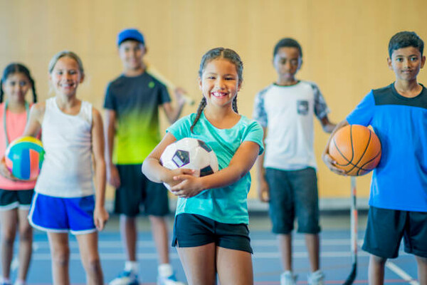 several young students holding a variety of sporting equipment