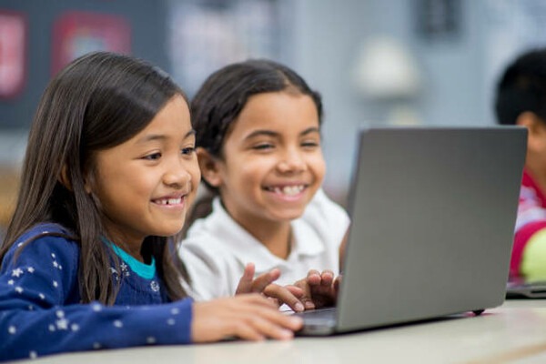 two young girls working on a laptop